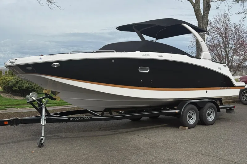The Image of 2019 Four Winns HD270 boat on trailer, black and white design, parked outdoors. - 0