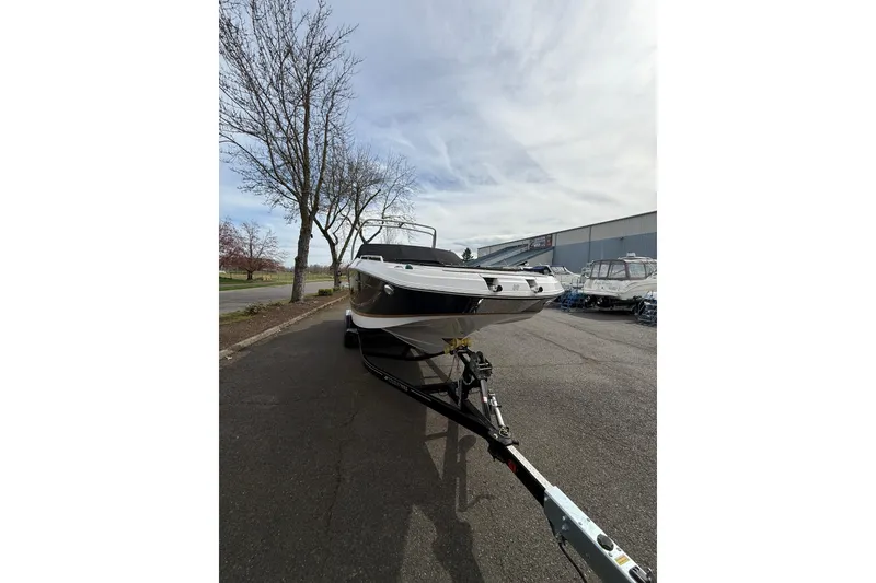 Slide: The Image of 2019 Four Winns HD270 boat on trailer, parked outdoors near trees and buildings. - 48
