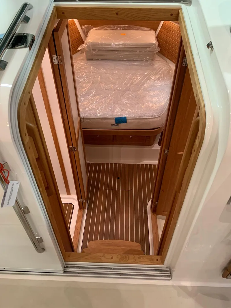 Slide: The Image of 2027 Back Cove 34O Hardtop Express cabin interior with wooden finish and cozy bed. - 12