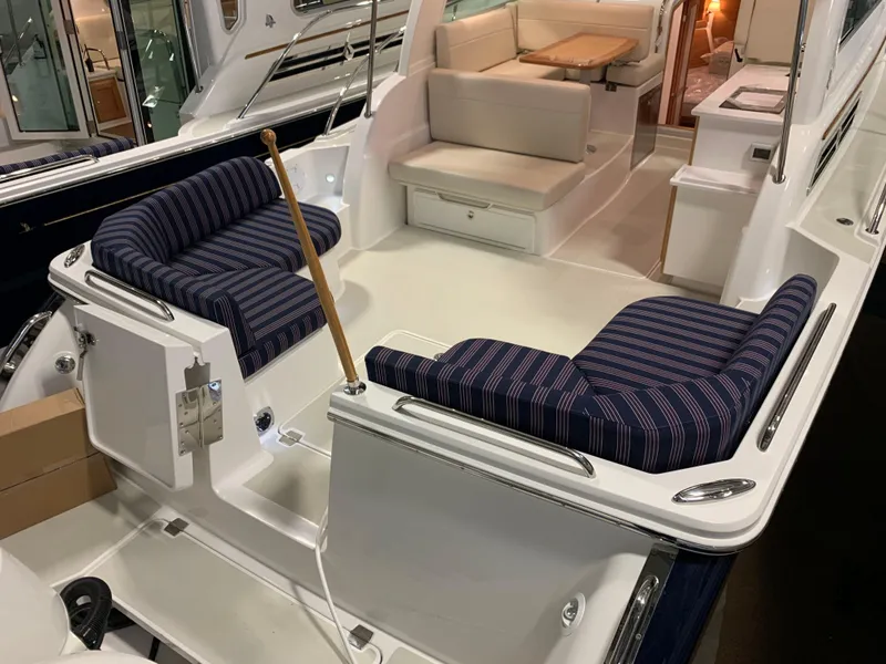 Slide: The Image of 2027 Back Cove 34O Hardtop Express boat interior with striped seating and dining area. - 2