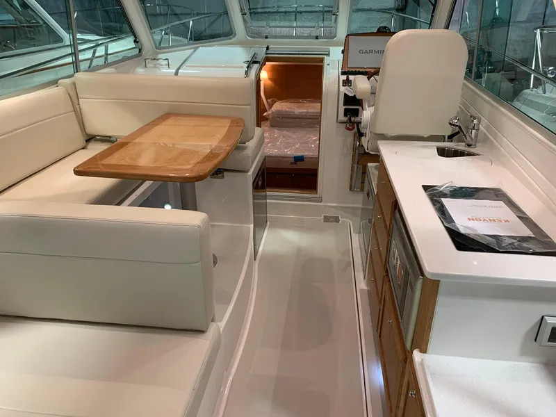 Slide: The Image of 2027 Back Cove 34O Hardtop Express interior with seating, table, and kitchenette. - 4