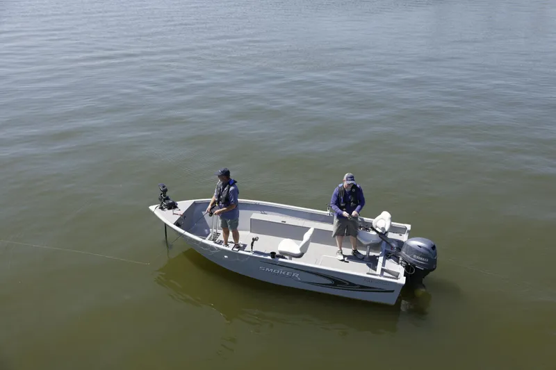 Slide: The Image of 2023 Smoker Craft Freedom 16 tiller deep V boat on calm water, two people fishing. - 21