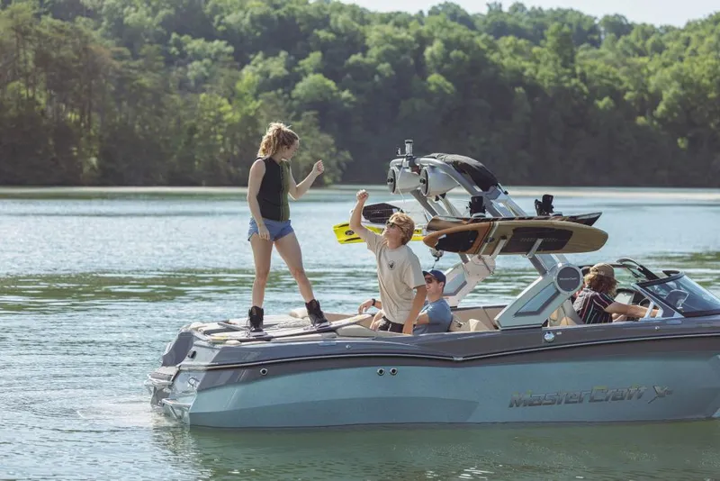 Slide: The Image of 2023 MasterCraft XStar boat with people enjoying water activities on a lake. - 4