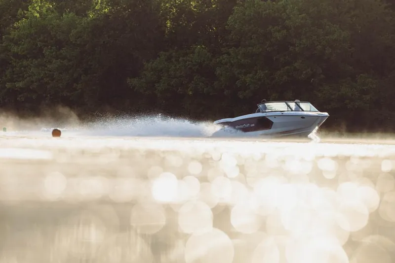 Slide: The Image of 2023 MasterCraft ProStar boat speeding on a lake with trees in the background. - 3