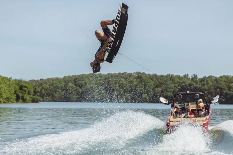 Slide: The Image of Wakeboarder performing a flip behind a 2023 MasterCraft X24 boat on a lake. - 15