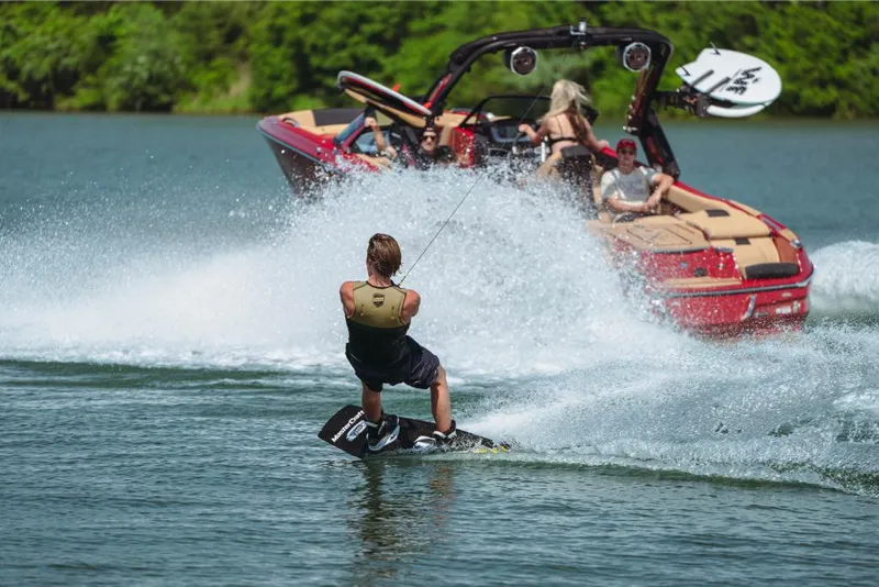 Slide: The Image of Person wakeboarding behind a 2023 MasterCraft X24 boat on a lake. - 2