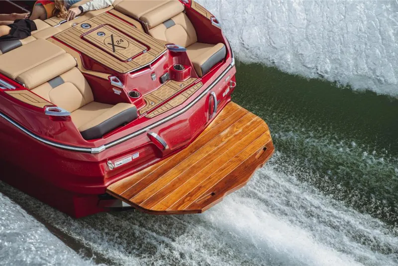Slide: The Image of 2023 MasterCraft X24 boat with teak swim platform on water. - 3