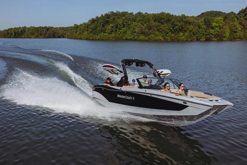 Slide: The Image of 2023 MasterCraft X26 boat cruising on a lake with passengers. - 0