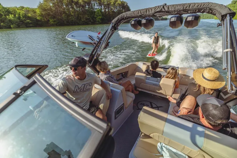 Slide: The Image of 2023 MasterCraft X26 boat with passengers enjoying wakeboarding on a sunny lake. - 5