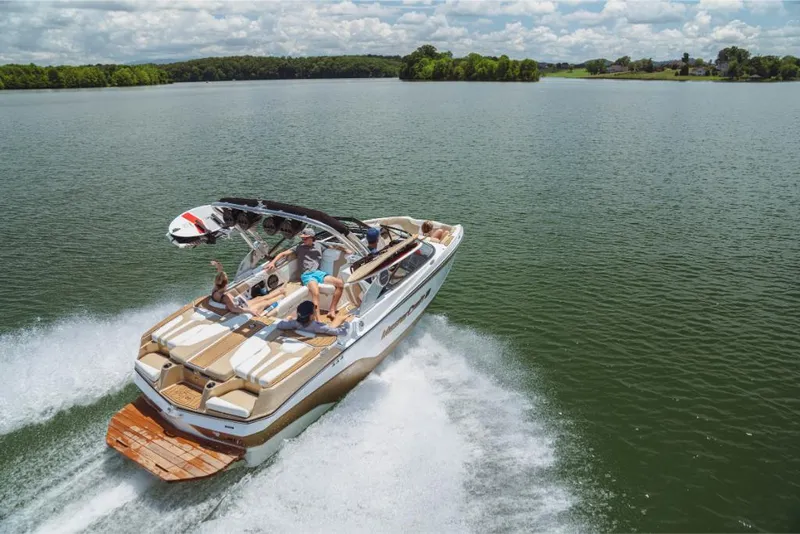 Slide: The Image of 2023 MasterCraft XT20 boat cruising on a lake with passengers enjoying the ride. - 0