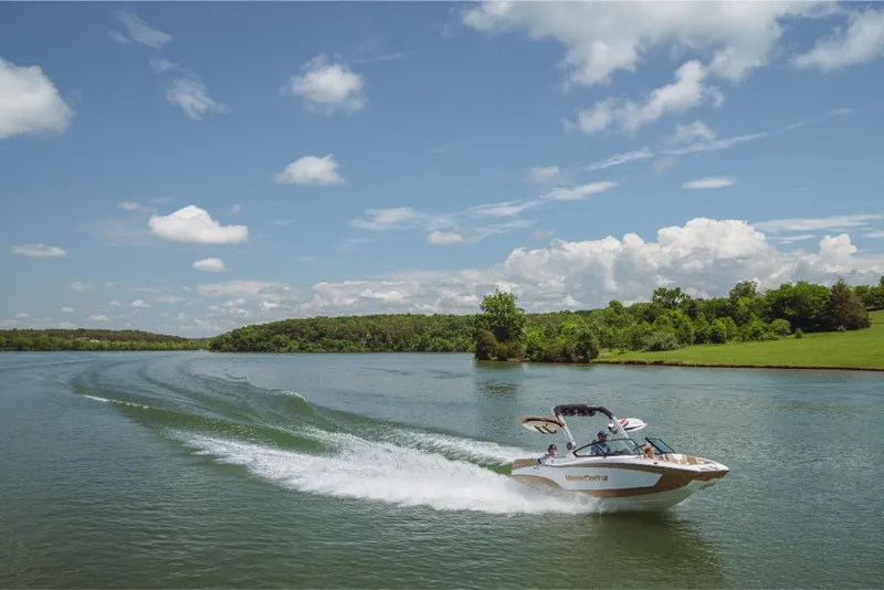 Slide: The Image of 2023 MasterCraft XT20 boat cruising on a scenic lake under a blue sky. - 4