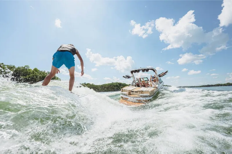 Slide: The Image of Person wakesurfing behind a 2023 MasterCraft XT20 boat on a sunny day. - 6