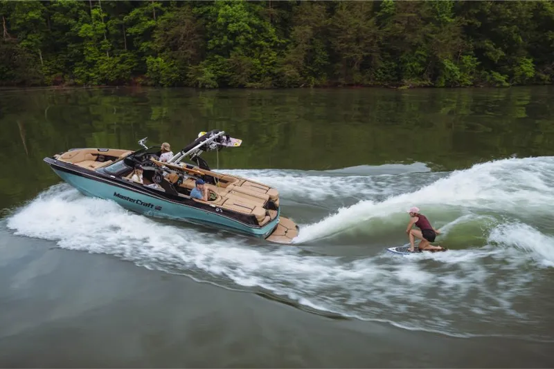 Slide: The Image of 2023 MasterCraft XT22 boat towing a wakeboarder on a lake. - 11