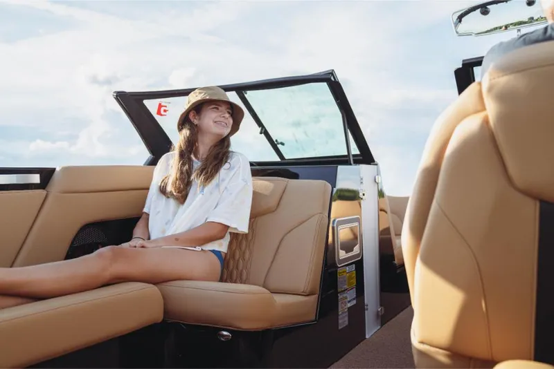 Slide: The Image of Young woman relaxing on a 2023 MasterCraft XT22 boat with tan leather seats. - 3