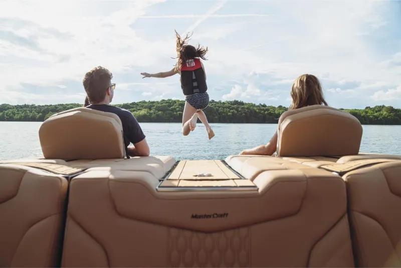 Slide: The Image of 2023 MasterCraft XT22 boat with people enjoying a lake, one jumping into the water. - 6