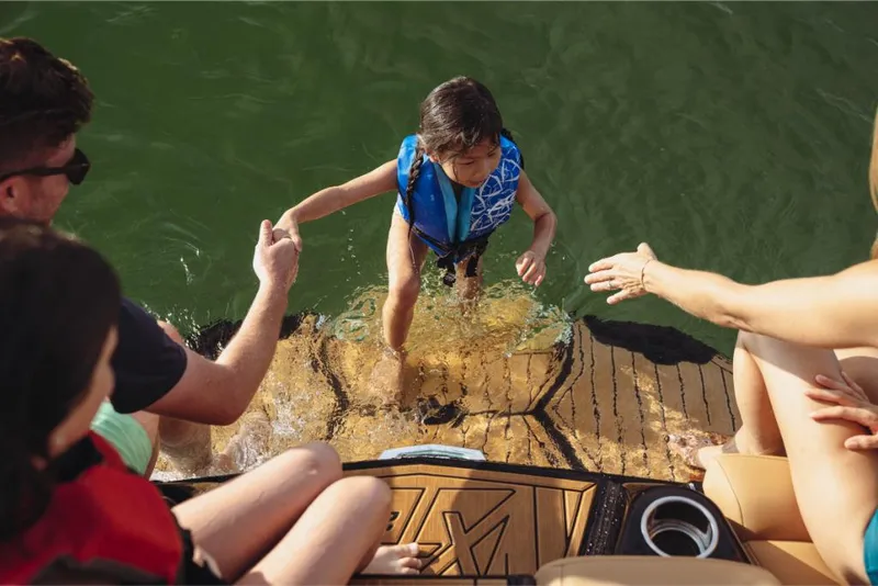 Slide: The Image of Child climbing onto MasterCraft XT22 boat, assisted by adults, 2023 model. - 7