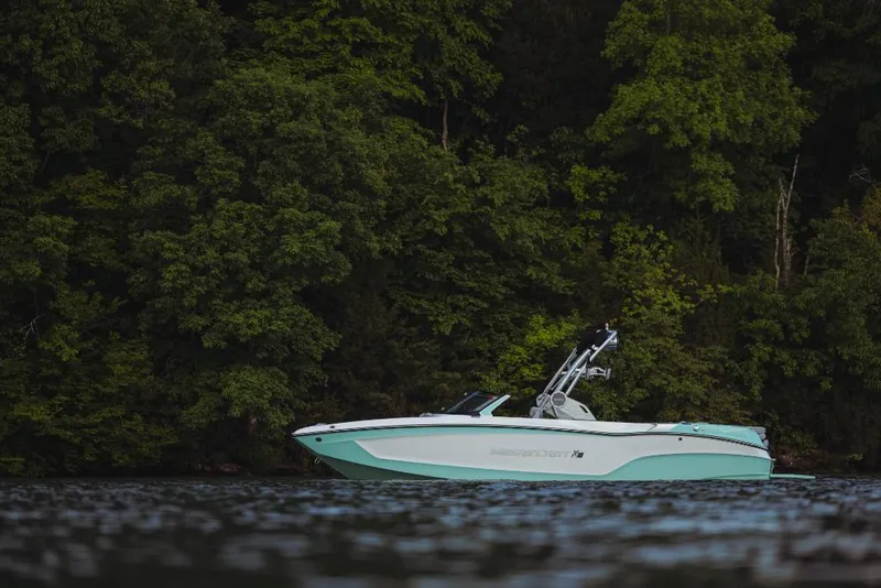 Slide: The Image of 2023 MasterCraft XT23 boat on a lake with a forested background. - 1