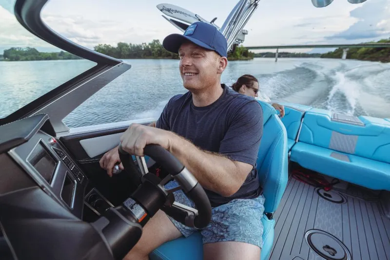 Slide: The Image of Man driving 2023 MasterCraft XT23 boat on a lake. - 18