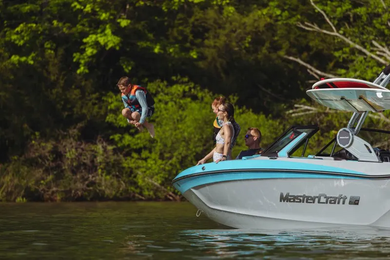 Slide: The Image of 2023 MasterCraft XT23 boat with people enjoying water activities. - 2
