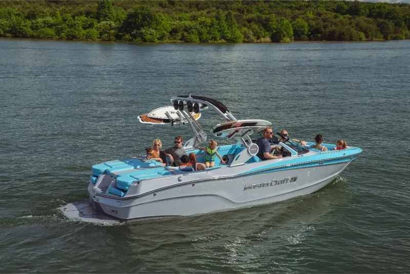Slide: The Image of 2023 MasterCraft XT23 boat cruising on a lake with passengers. - 3