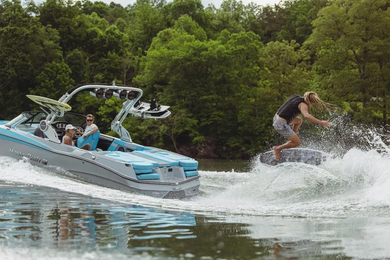 Slide: The Image of 2023 MasterCraft XT23 boat towing a wakeboarder on a scenic lake. - 7