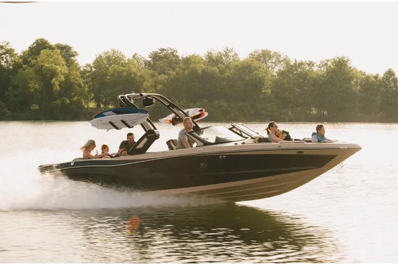 Slide: The Image of 2022 MasterCraft XT25 boat cruising on a lake with passengers enjoying the ride. - 0