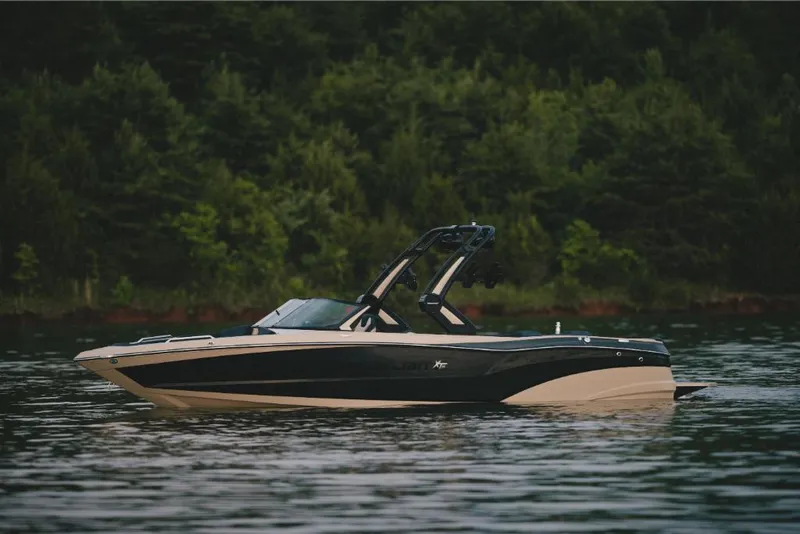Slide: The Image of 2022 MasterCraft XT25 boat on a calm lake with forest background. - 1