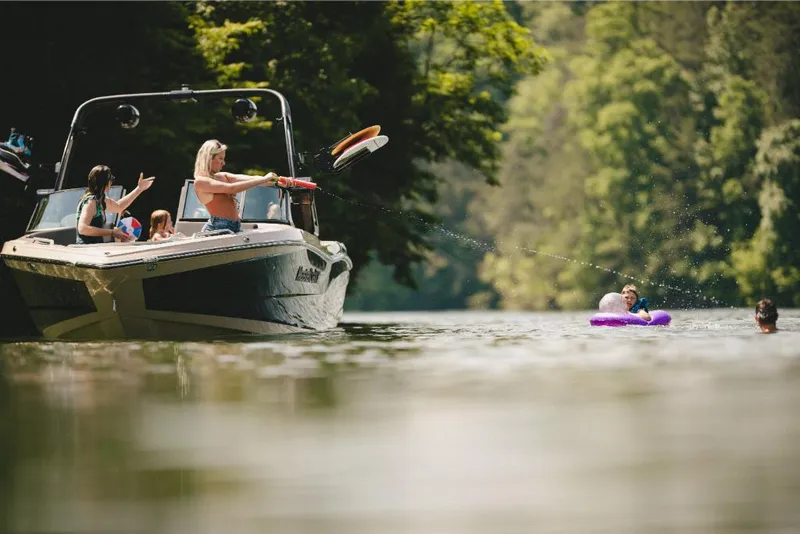 Slide: The Image of 2022 MasterCraft XT25 boat on a lake with people enjoying water activities. - 10