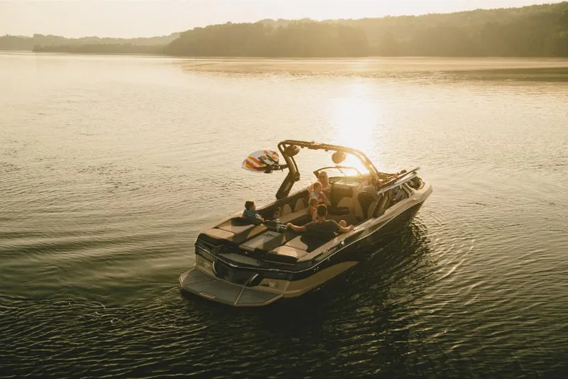 Slide: The Image of 2022 MasterCraft XT25 boat on a serene lake at sunset. - 2