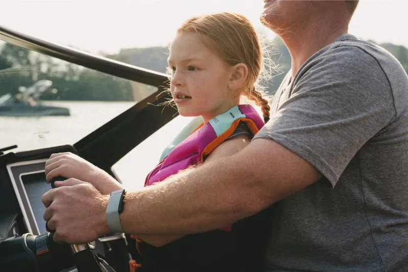 Slide: The Image of Child steering 2022 MasterCraft XT25 boat with adult supervision. - 4