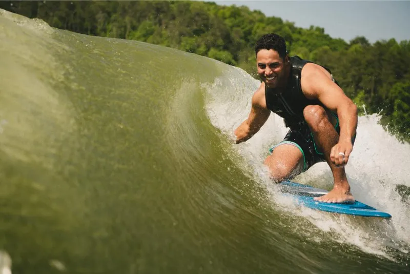 Slide: The Image of Man wakesurfing behind a 2022 MasterCraft XT25 boat on a sunny day. - 8