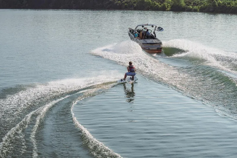 Slide: The Image of Person wakeboarding behind a 2023 MasterCraft NXT20 boat on a calm lake. - 1