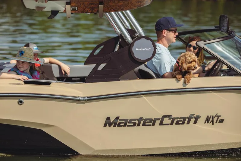 Slide: The Image of 2023 MasterCraft NXT20 boat with family and dog on a lake. - 12