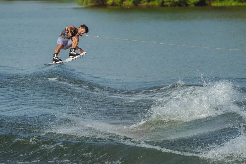Slide: The Image of Wakeboarder performing trick behind 2023 MasterCraft NXT20 boat on a lake. - 3