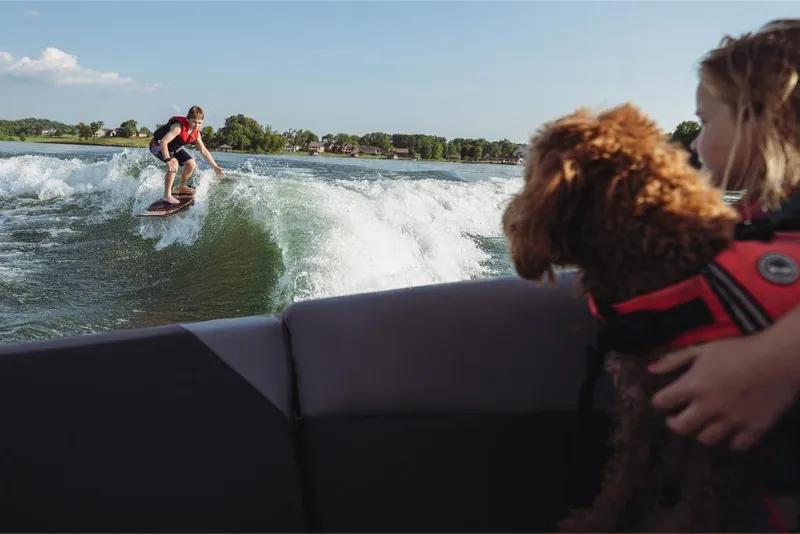 Slide: The Image of Person wakesurfing behind a 2023 MasterCraft NXT20 boat, watched by a child and dog. - 7