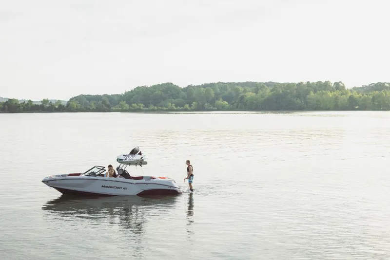 Slide: The Image of 2023 MasterCraft NXT22 boat on a serene lake with people enjoying the water. - 15