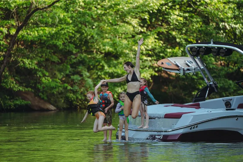 Slide: The Image of Family enjoying water activities on a 2023 MasterCraft NXT22 boat. - 2