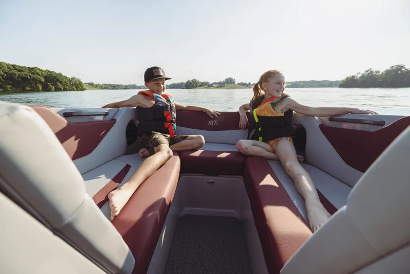 Slide: The Image of 2023 MasterCraft NXT22 boat with children enjoying the seating area on a sunny day. - 5