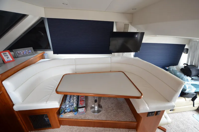 Slide: The Image of 1995 Carver 370 Voyager interior dining area with white leather seating and mounted TV. - 18