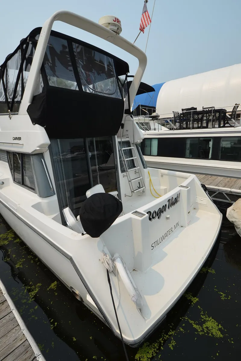 Slide: The Image of 1995 Carver 370 Voyager docked, rear view with black canopy and American flag. - 6