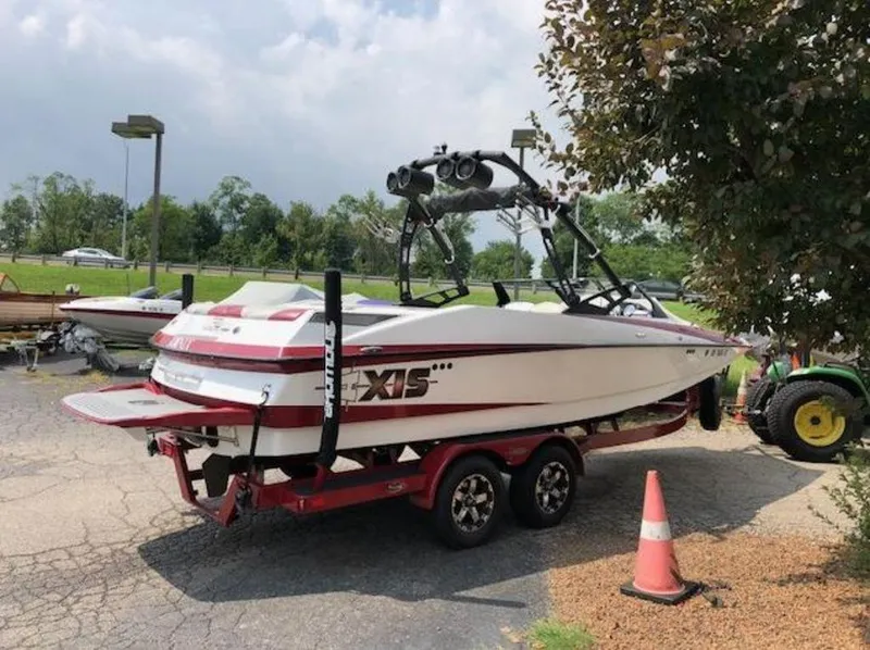 Slide: The Image of 2012 Axis Wake Research A-22 boat on trailer, parked outdoors near trees. - 36