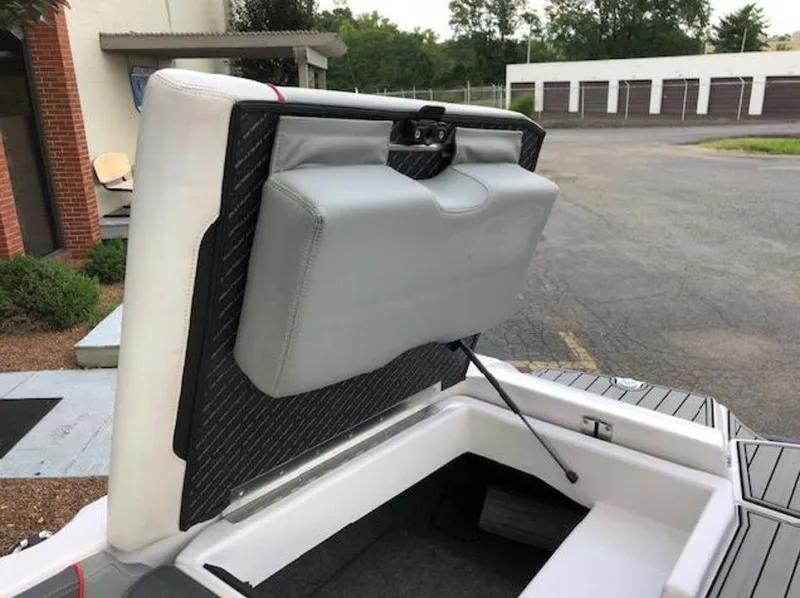 Slide: The Image of 2013 Nautique Super Air Nautique 230 boat seat storage compartment open in parking lot. - 7