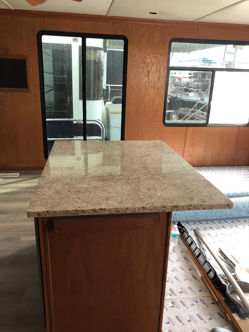 Slide: The Image of Granite countertop inside 2004 Sumerset Wind Walker houseboat, featuring wood paneling and large windows. - 8