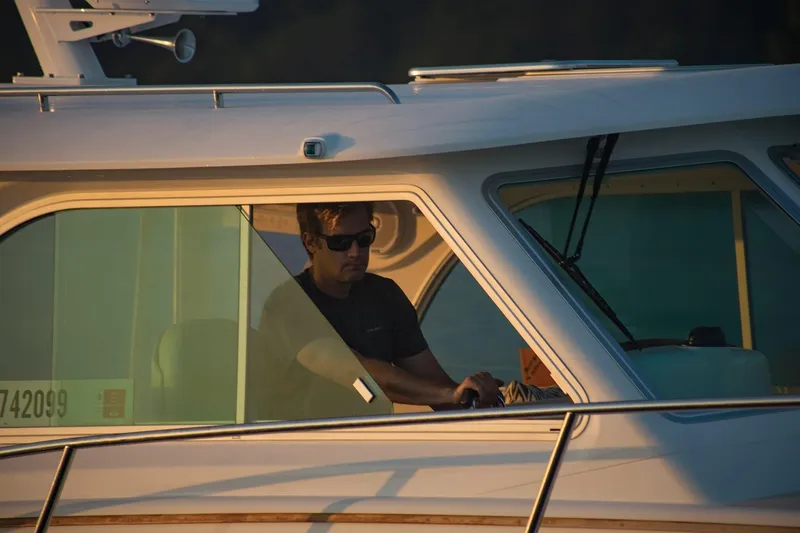 Slide: The Image of Man piloting a 2024 Back Cove 34O boat at sunset. - 14