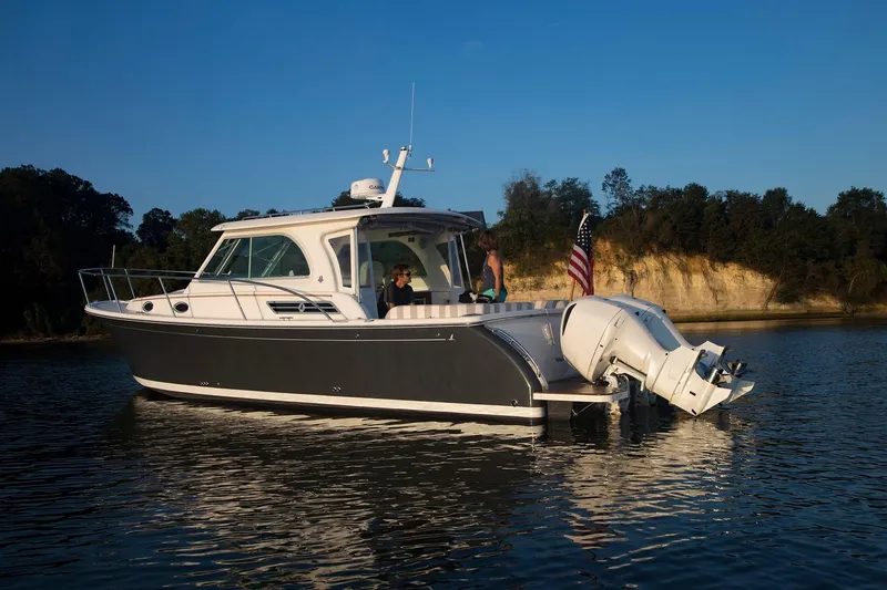Slide: The Image of 2024 Back Cove 34O boat cruising on a calm lake with passengers onboard. - 3