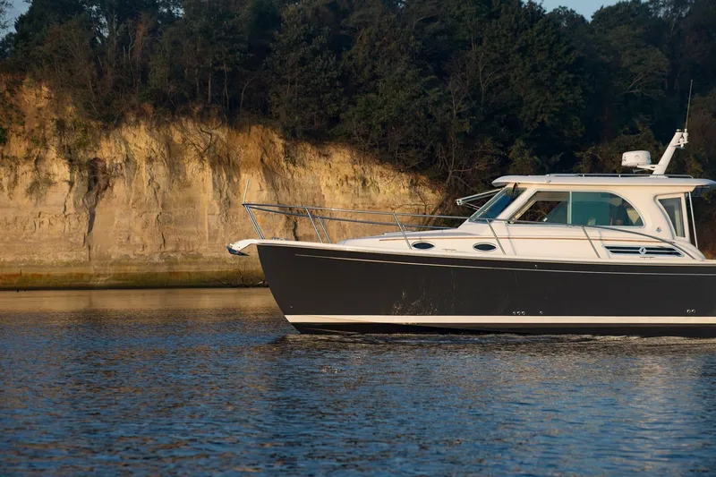 Slide: The Image of 2024 Back Cove 34O boat cruising near a rocky shoreline. - 6