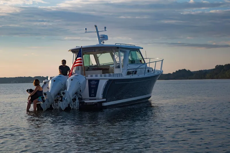 Slide: The Image of 2024 Back Cove 34O boat on calm water at sunset with people onboard. - 8