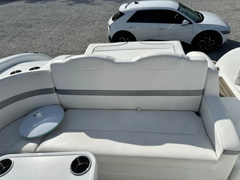 Slide: The Image of 2012 Formula 350 Sun Sport boat interior with white seating, cup holders, and a parked car nearby. - 6