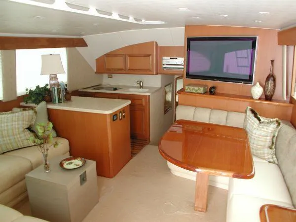 Slide: The Image of 2024 Jersey Cape 44' Custom yacht interior with kitchen, dining area, and TV. - 5