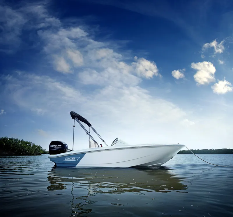 Slide: The Image of 2023 Boston Whaler 130 Super Sport boat on calm water under a blue sky. - 1